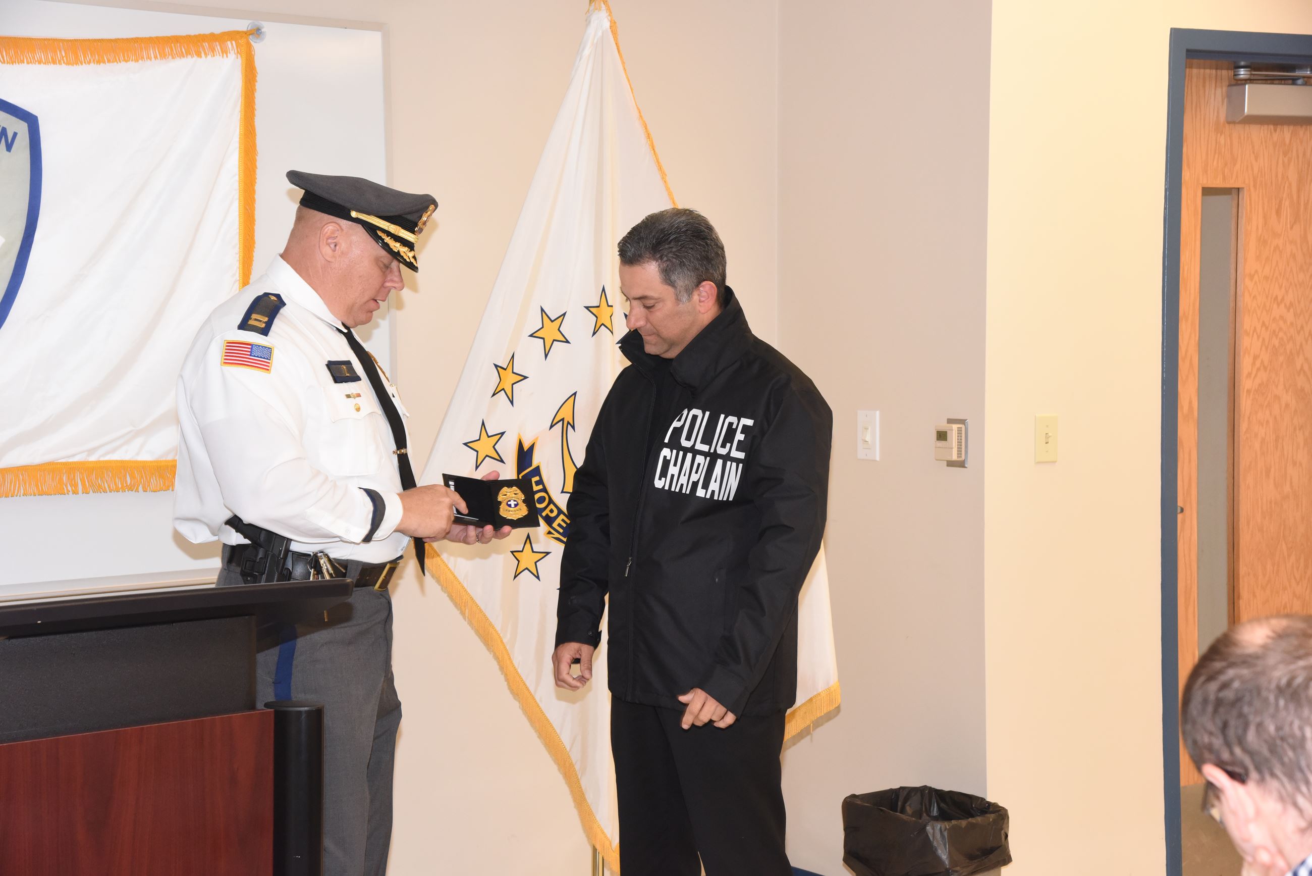 A police officer presenting a badge to a new police chaplain during a ceremony.